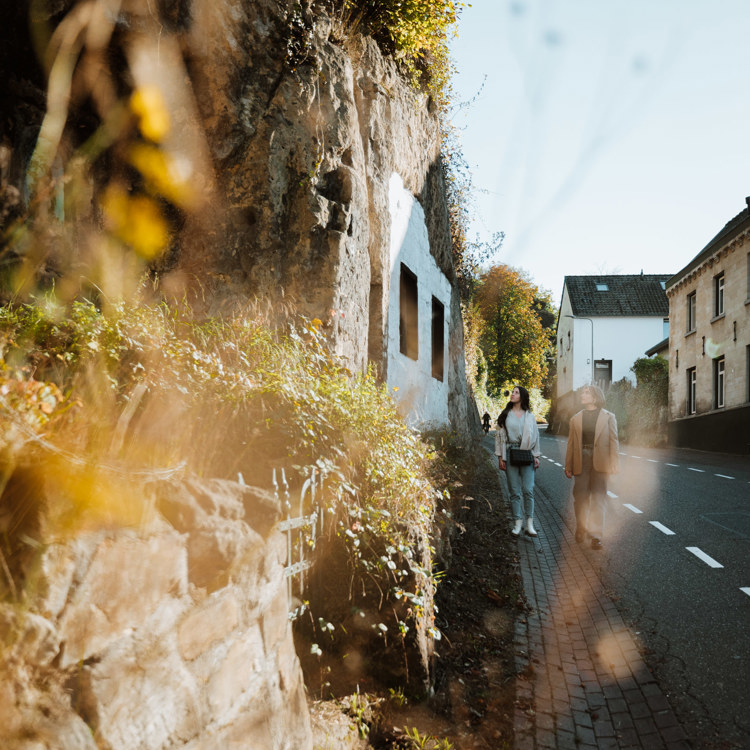 Twee vriendinnen lopen de Geulhemmerberg af en bekijken de rotswoningen langs te weg.