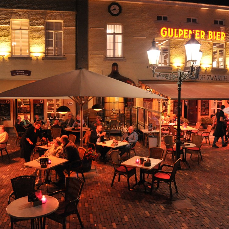Mensen eten en drinken op een terras in het donker