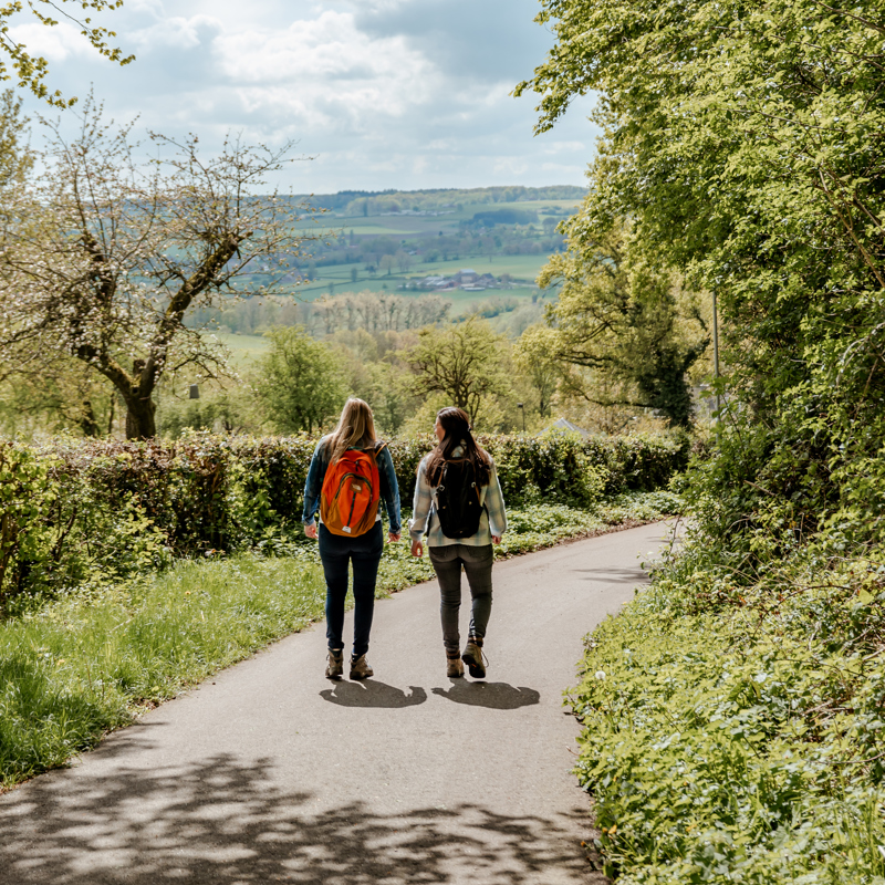 Twee sportieve vrouwen wandelen door heuvellandschap op een mooie lentedag