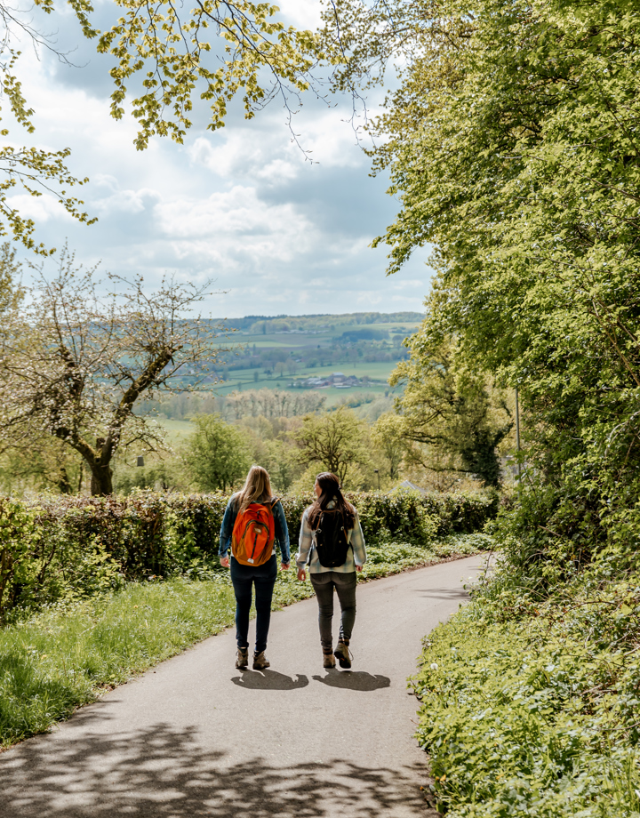 Twee sportieve vrouwen wandelen door heuvellandschap op een mooie lentedag