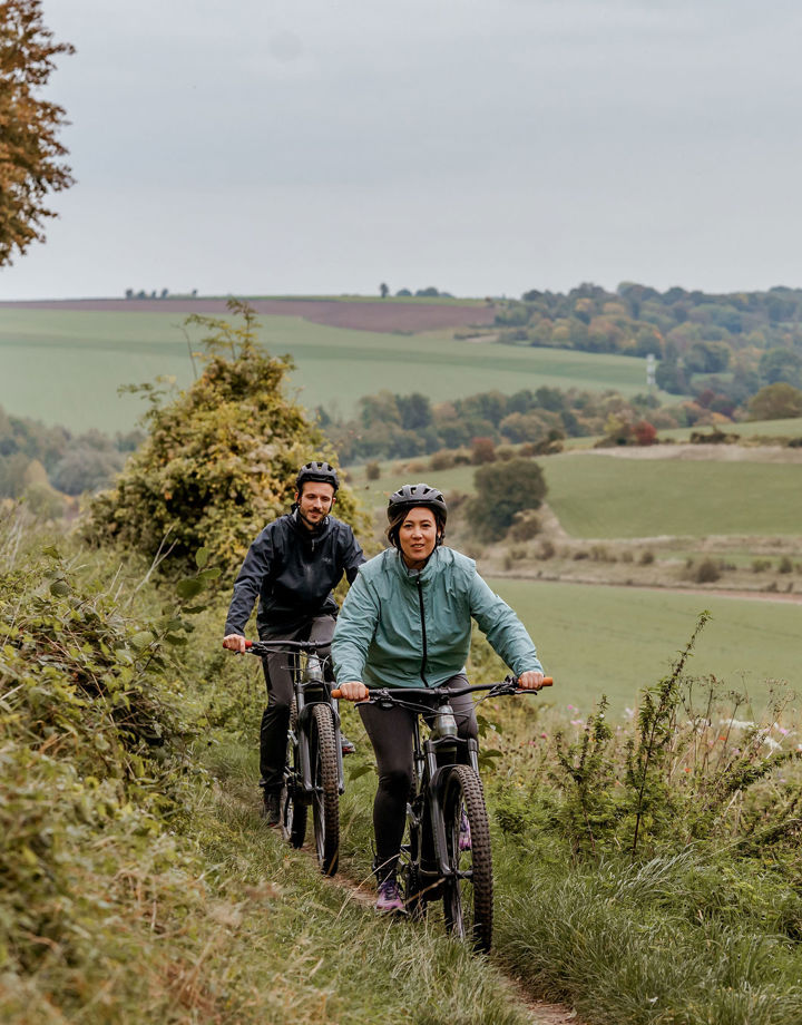 Koppel op mountainbike fietst achter elkaar op een smal pad in het Heuvelland.