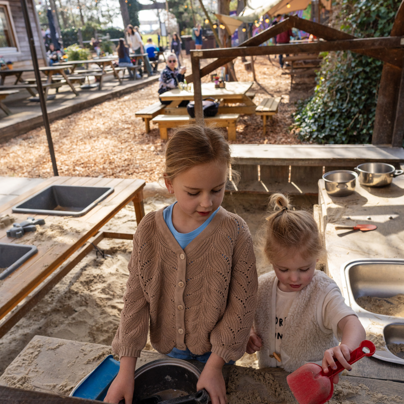 Twee meisjes spelen met zand in een speelhoek bij de blotevoetenhut in Brunssum.