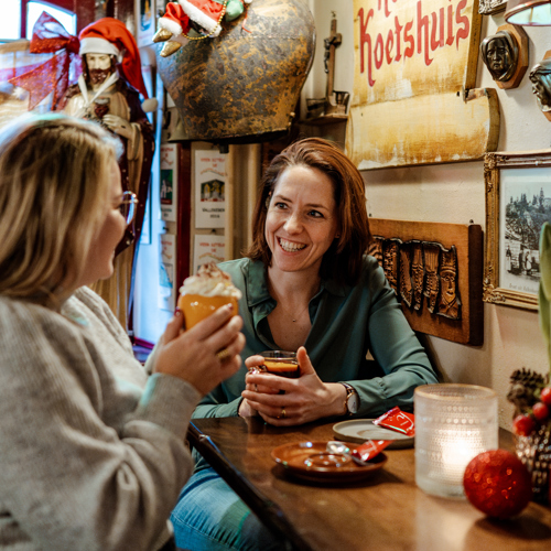 Twee mensen die drankje drinken in cafe aan hoge tafel
