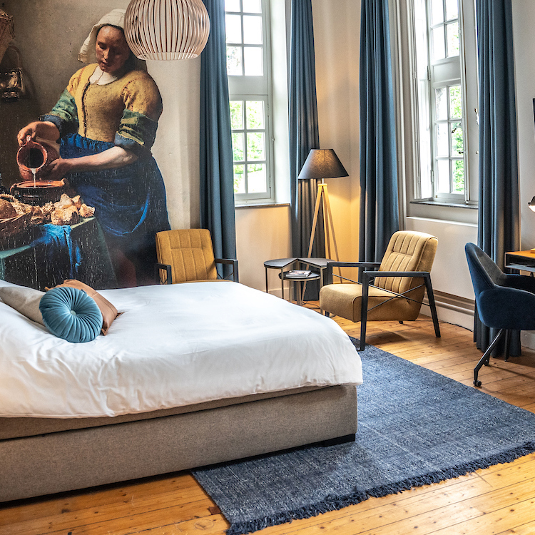 Sfeervolle hotelkamer in een bijzonder B&B met een poster van het Melkmeisje op de muur.