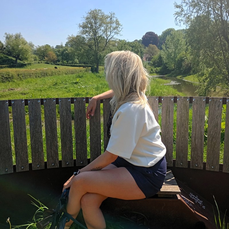 Vrouw geniet op een bankje van uitzicht met haar hondje aan de lijn.