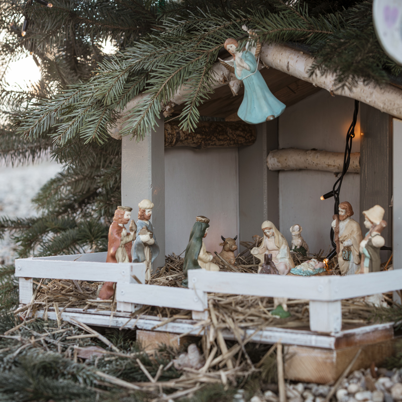 Miniatuur kerstpoppetjes in miniatuur kerstschuur op grind met dennentakken