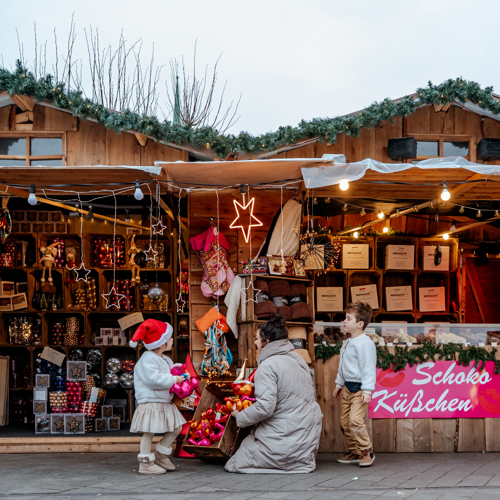 Moeder met kinderen voor een kraam van Santa's village kerstmarkt met kerstproducten