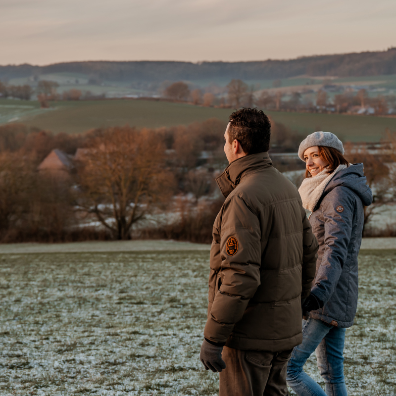 Man en vrouw wandelend door het Heuvelland in weiland in de winter 