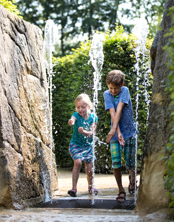 Kinderen rennen door fontein bij het Drielandenpunt doolhof