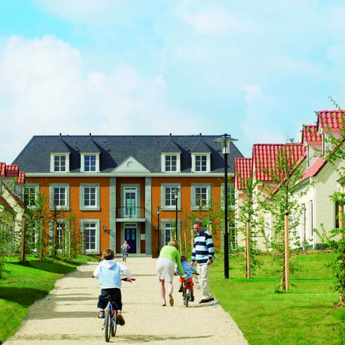 Mensen lopen op Grindpad in bungalowpark met aan beide kanten vakantiehuisjes.