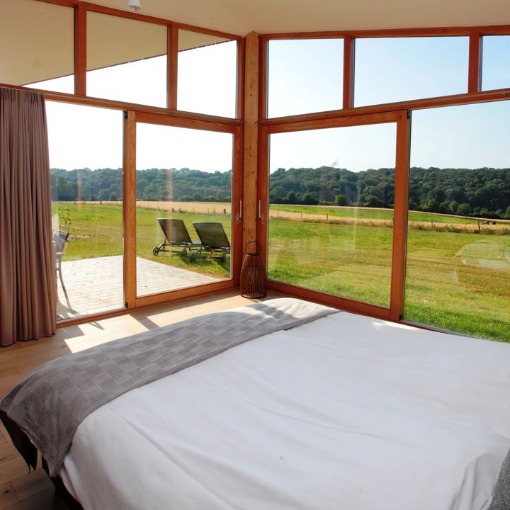 Een bed in een kamer met ramen en uitzicht over het landschap