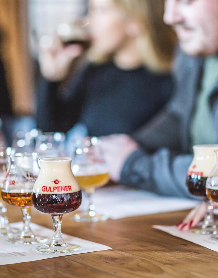 Mensen met ieder 3 proefglaasjes met Gulpener bieren voor zich