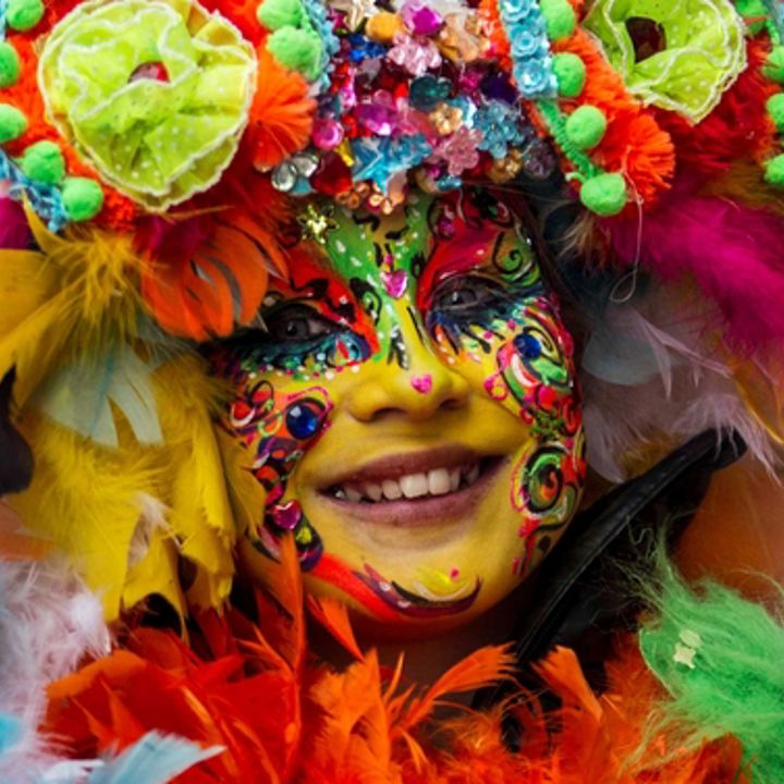 Vrouw draagt veelkleurig pakje en schminck met Carnaval