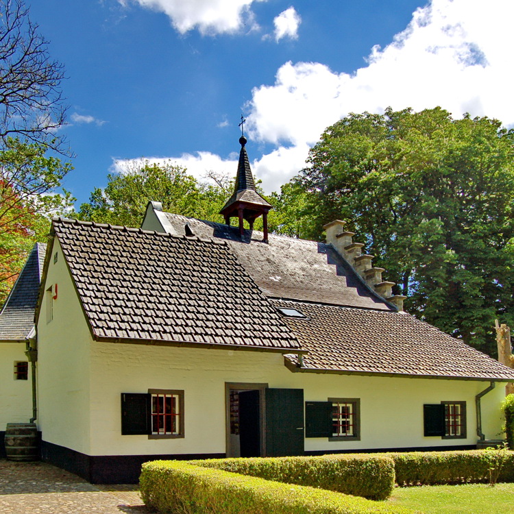 Voorkant van de kluizenaarswoning op de Schaesberg op een zomerse dag met witte wolken