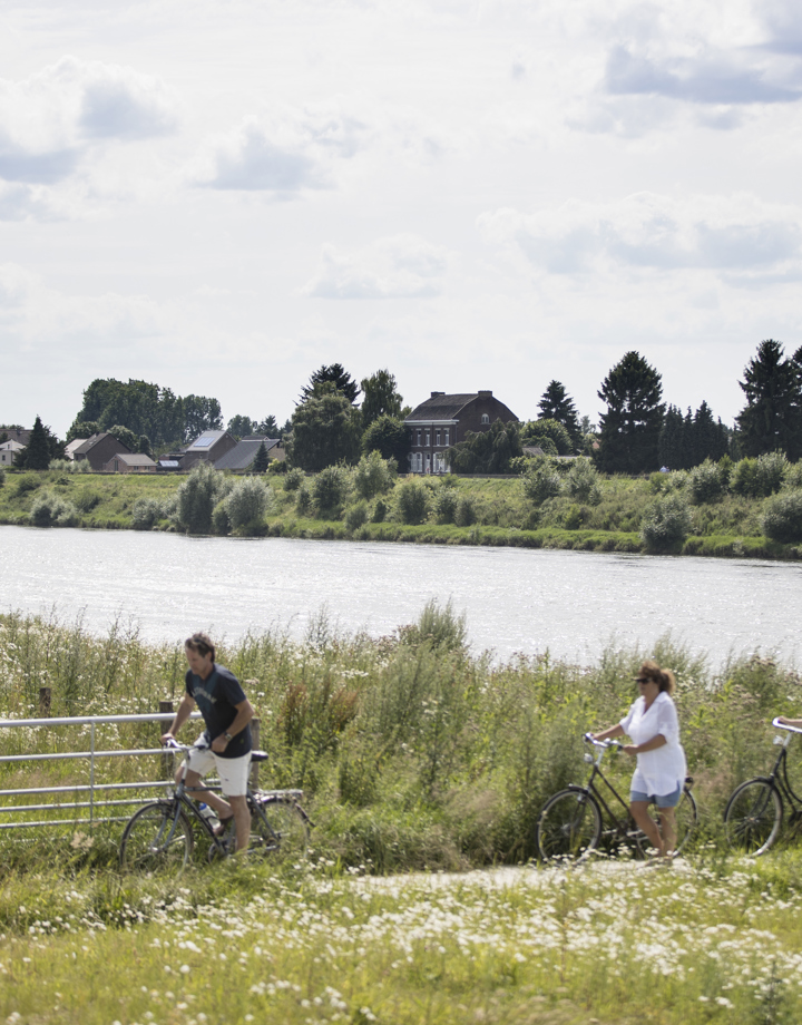 Mensen op fiets en wandelaars bij de Maas