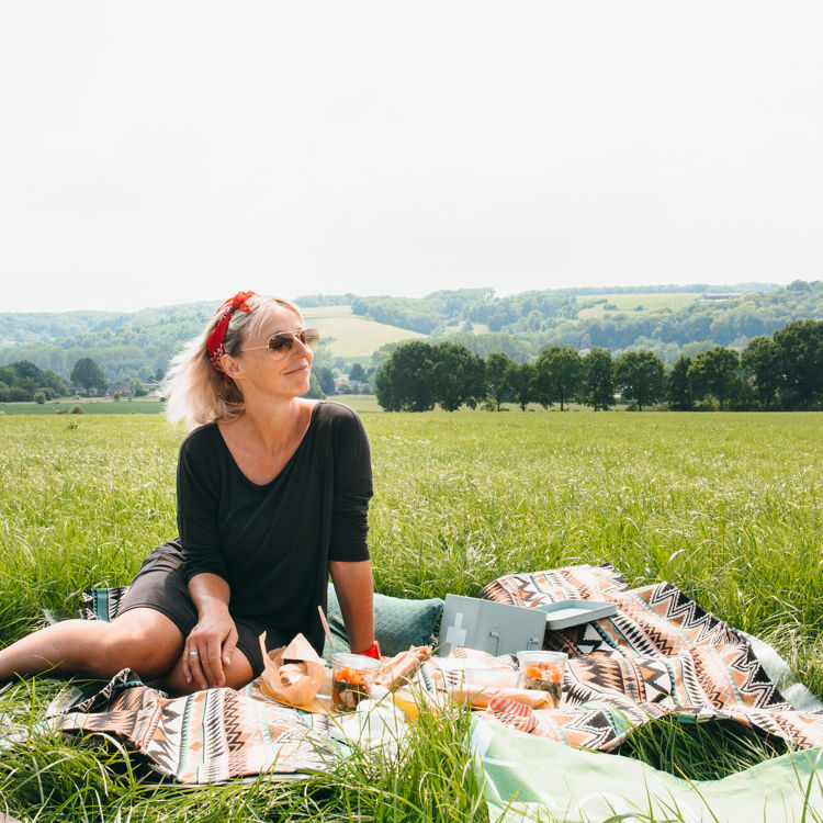 Vrouw zittende op picknickdeken met achterliggend heuvellandschap