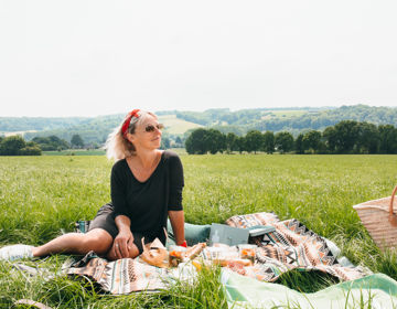 Vrouw zittende op picknickdeken met achterliggend heuvellandschap