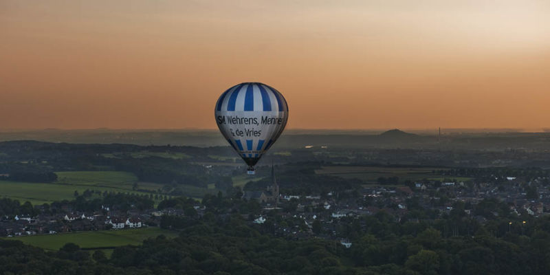 Luchtballon Boven Zuid Limburgs Heuvelland met een oranje lucht