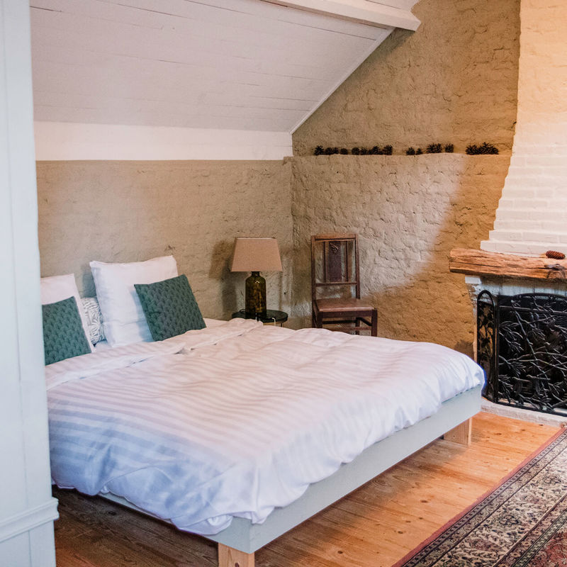 Villa De Proosdij slaapkamer opgemaakt bed met kachel