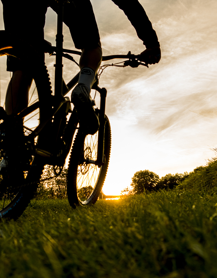 Een close up van de mountainbike wielen en gras tijdens een zonsondergang