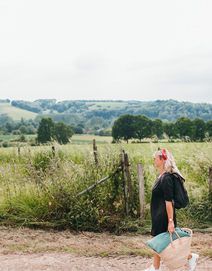 Vrouw wandelend met picknicktas en achterliggend heuvellandschap