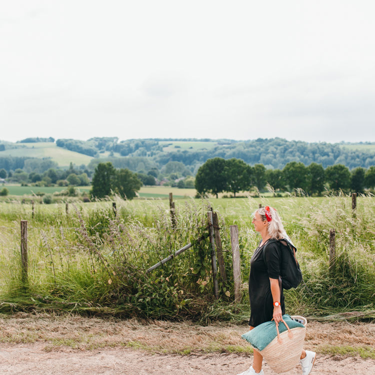 Vrouw wandelend met picknicktas en achterliggend heuvellandschap