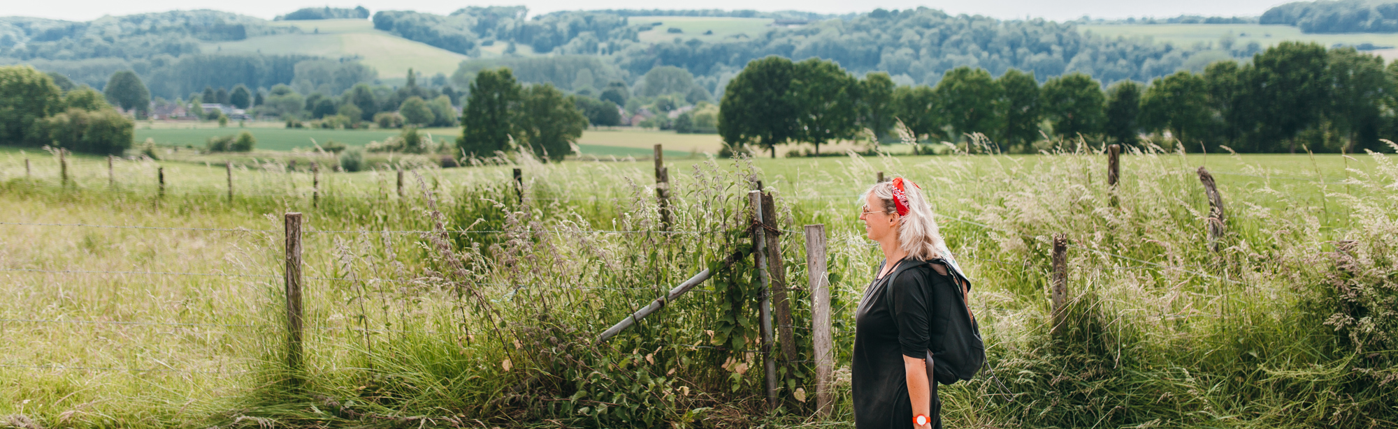 Vrouw wandelend met picknicktas en achterliggend heuvellandschap