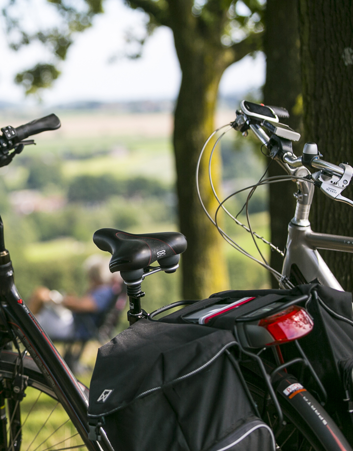 Close up van twee fietsen met op de achtergrond twee mensen op een bankje die genieten van het uitzicht