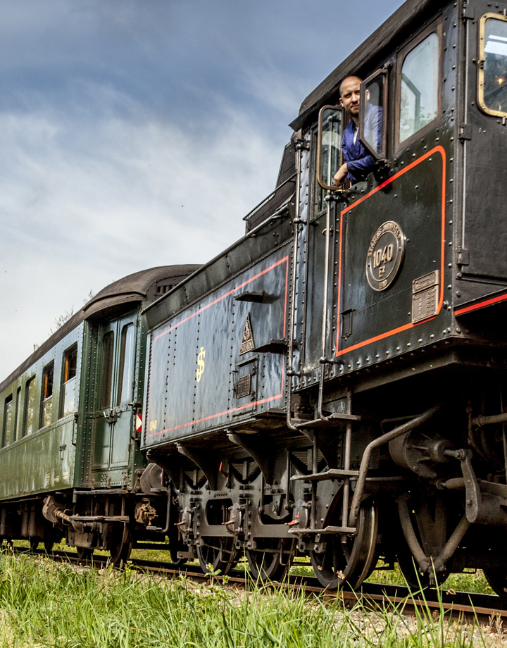 Zicht op de Miljoenenlijn Stoomtrein locomotief en treinstellen. Uit locomotief hangt de machinist.