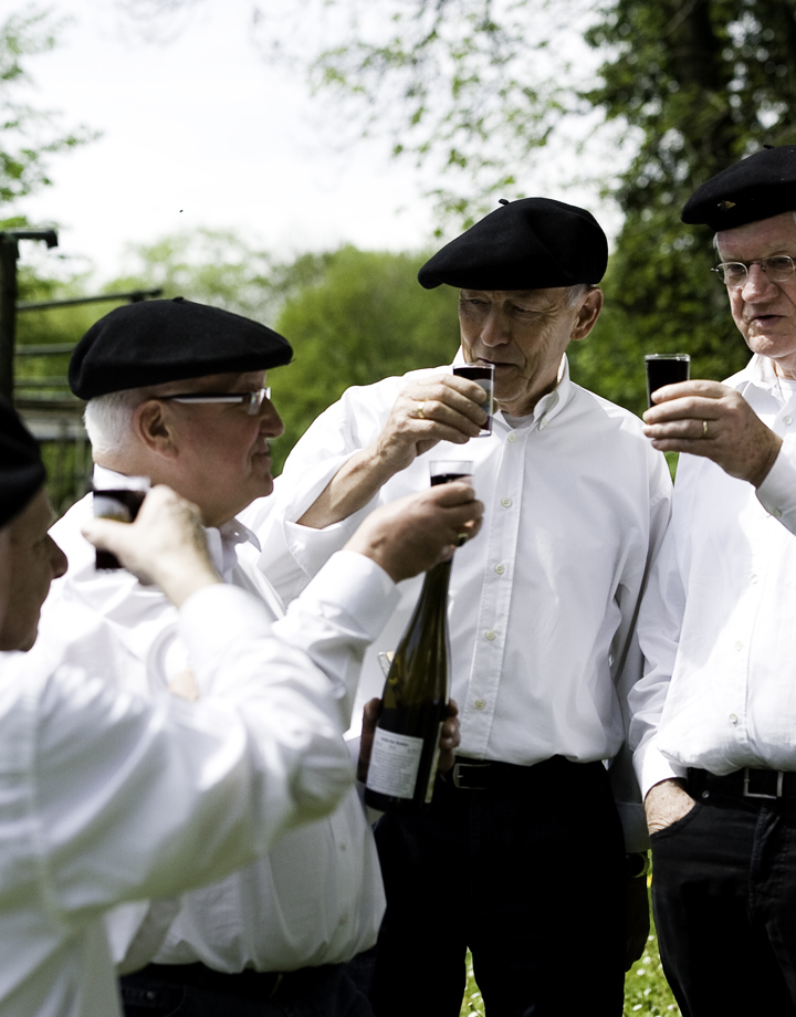 Wijnboeren in zondagse kleding proosten bij Wijngaard Deelgaarderberg met een lokaal wijntje
