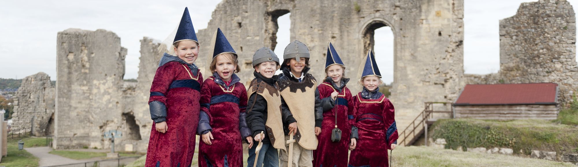 Groep kinderen staan verkleed boven op de kasteelruine in Valkenburg