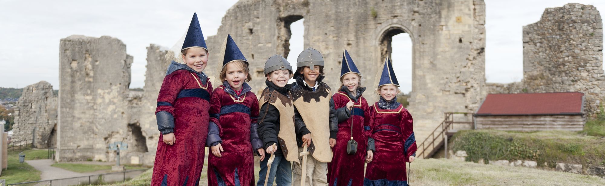Groep kinderen staan verkleed boven op de kasteelruine in Valkenburg