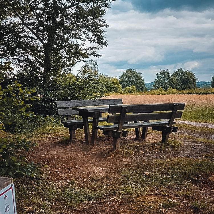 Picknickplek in relatief open veld met wandelpaal van de Rode Route in Noorbeek