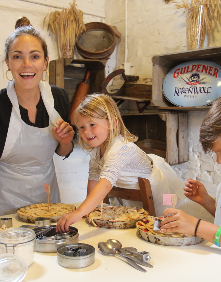 Vrouw en twee kinderen bakken een vlaai bij de Bisschopsmolen