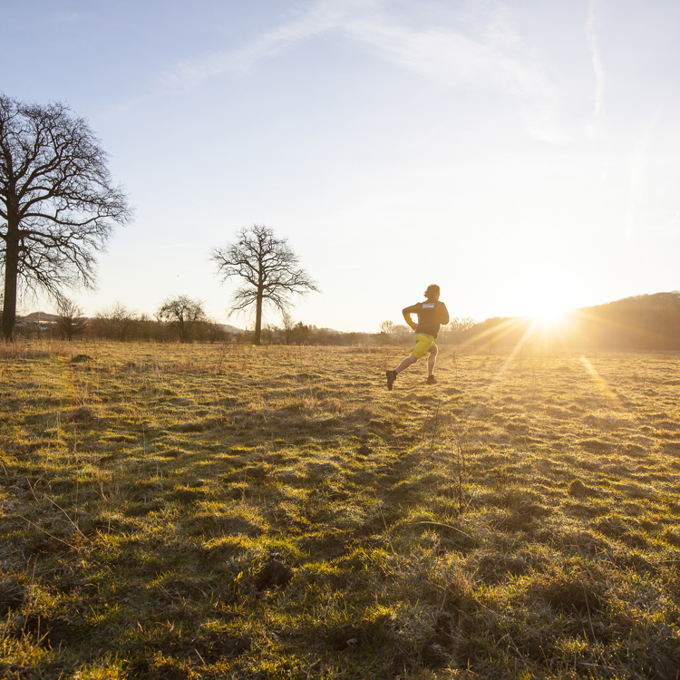 Een hardloper rent over de heide tijdens zonsondergang