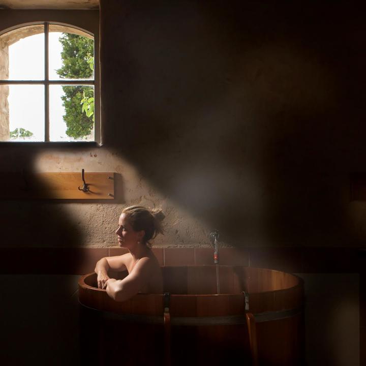 Dame zit in bad in donkere wellness omgeving.