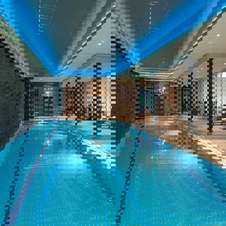 binnenzwembad in wellness met ligstoeltjes aan de zijkant. 