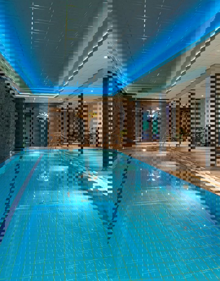 binnenzwembad in wellness met ligstoeltjes aan de zijkant. 