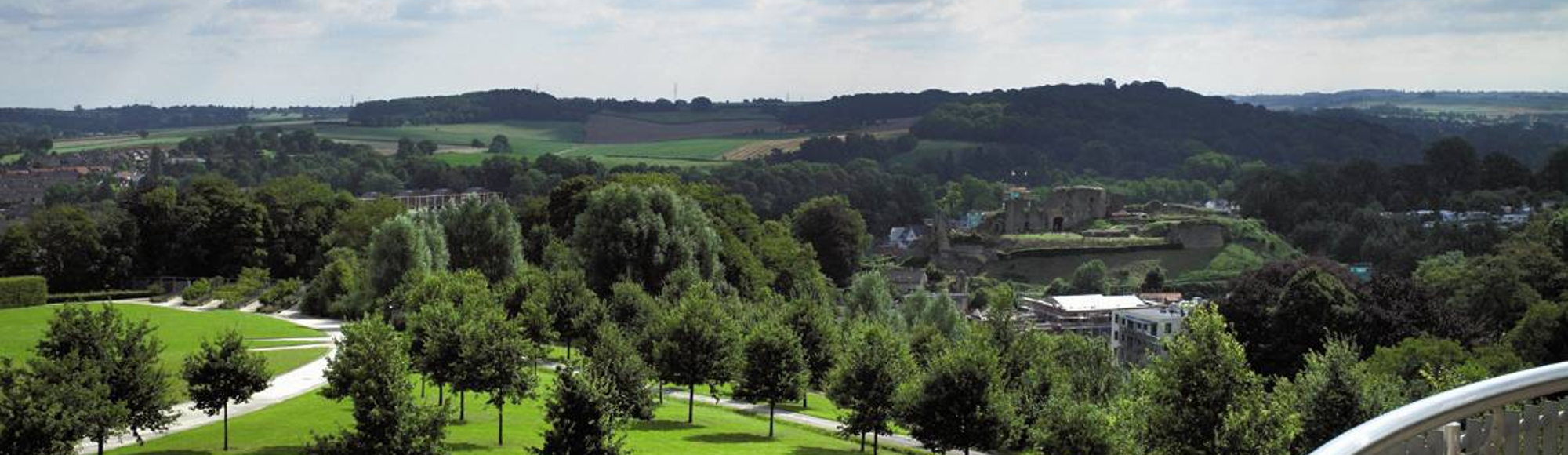 uitzicht vanaf een balkon over een park met bomen. 