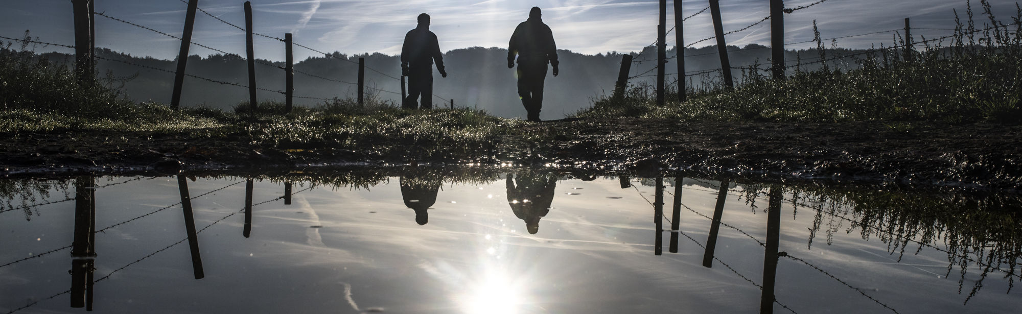 Wandelaars met reflectie in een waterplas