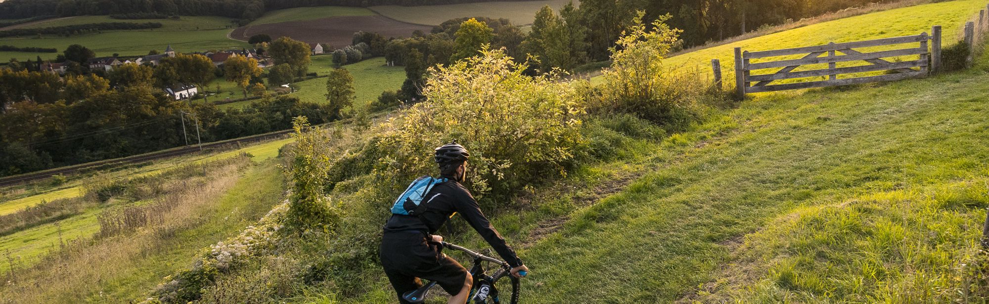 Mountainbiker fietst bergje op met zonsopkomst