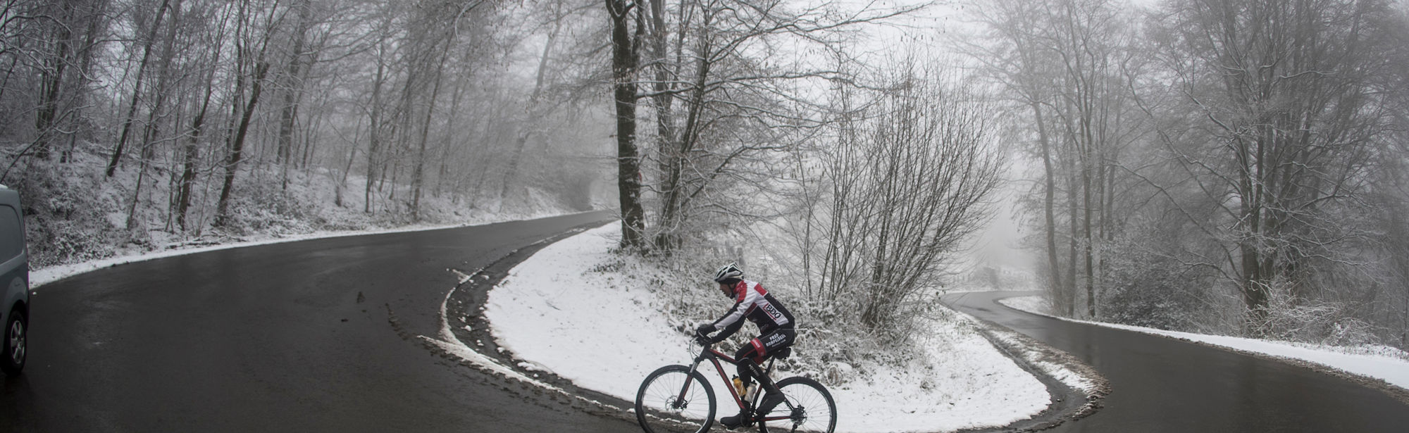Een fietser beklimt een pittige heuvel in de sneeuw