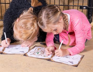Twee kinderen kleuren in een boekje in de mergelgrotten