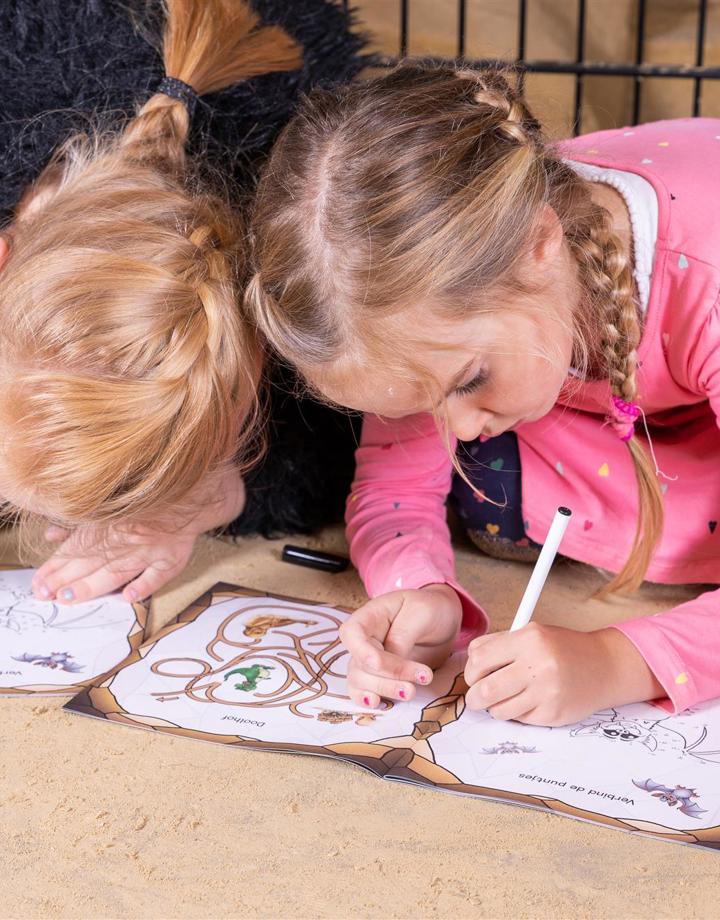 Twee kinderen kleuren in een boekje in de mergelgrotten