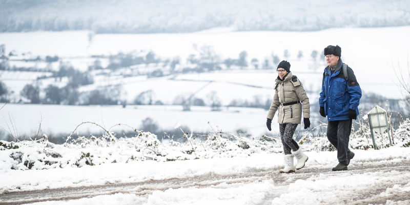 Twee wandelaars wandelen in een winterwonderlandschap met uitzicht over de witte heuvels