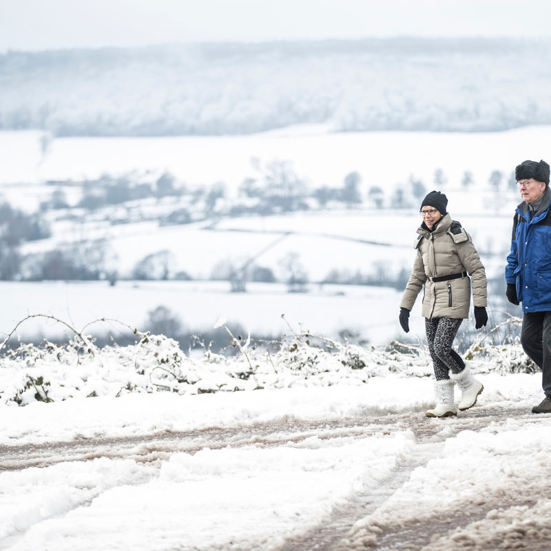 Twee wandelaars wandelen in een winterwonderlandschap met uitzicht over de witte heuvels