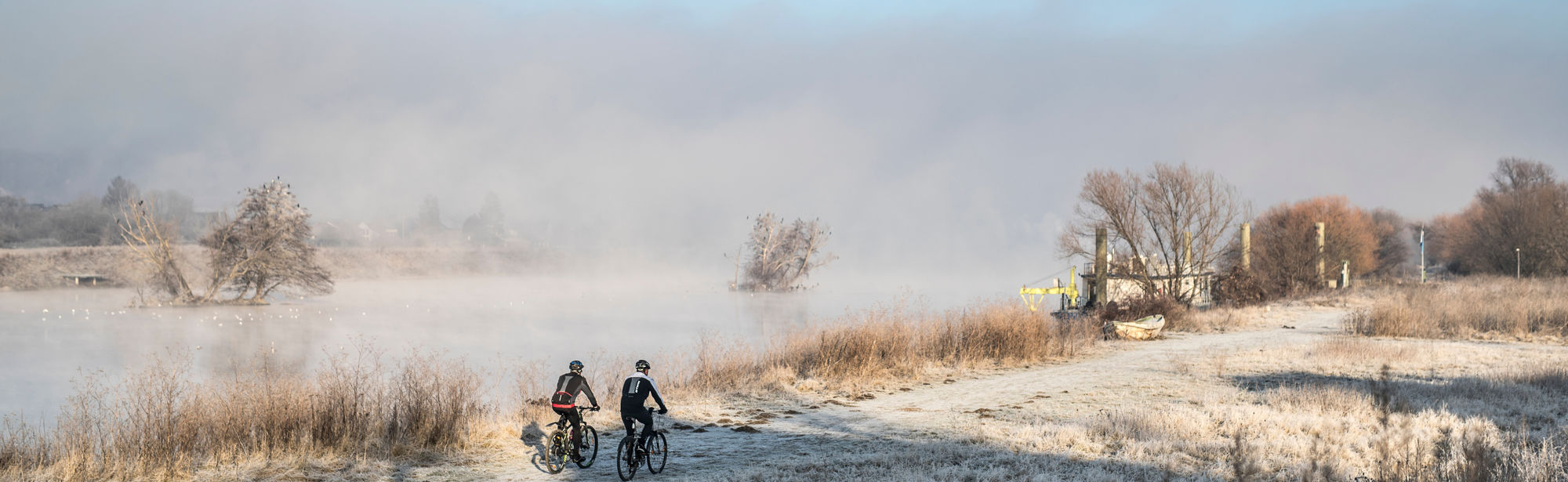 Mountainbiken in een winters landschap langs een mistige rivier