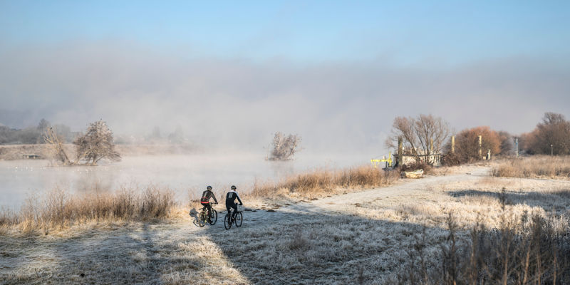 Mountainbiken in een winters landschap langs een mistige rivier