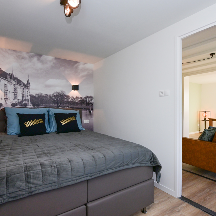 Slaapkamer van een vakantiewoning met een doorkijkje naar de woonkamer.