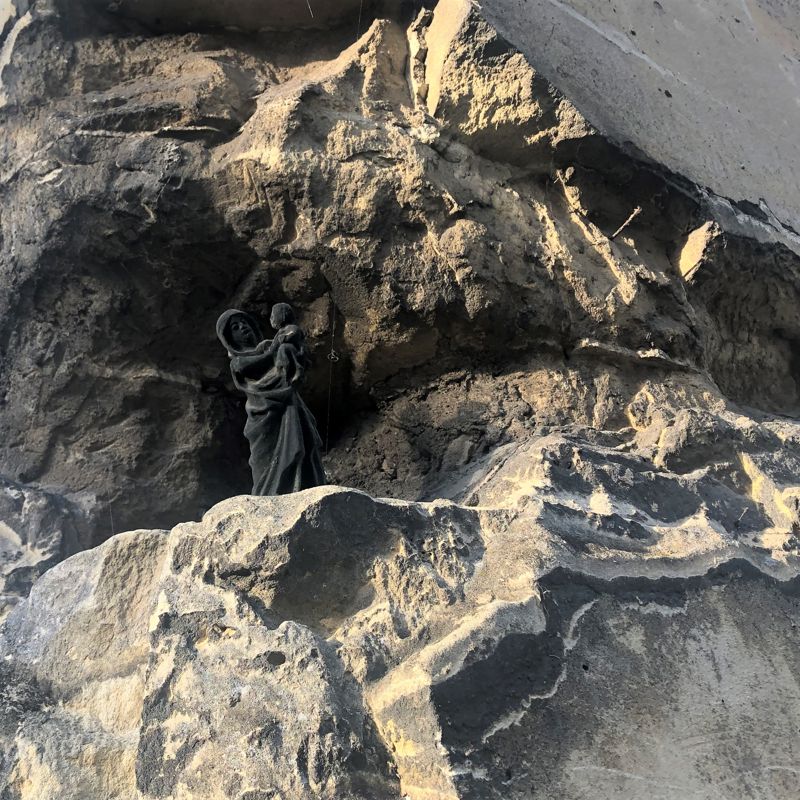 Een zwart mariabeeldje met kindje Jezus staat verstopt in de inkeping van afgebrokkelde muur